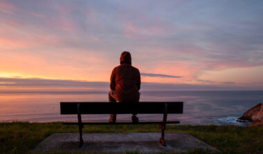 man sitting on bench overlooking the ocean