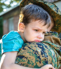 Child saying tearful goodbye to military parent before deployment