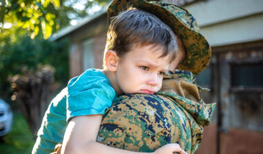 Child saying tearful goodbye to military parent before deployment